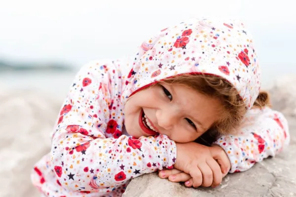 Nasmejana deklica na plaži v zgornjem delu s cvetličnim potiskom