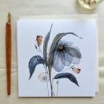 Sožalnica Clara z akvarelno ilustracijo sivomodre cvetlice ob peresu in kuverti