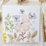 Beležka Nude 16x16 z mehko akvarelno ilustracijo cvetja in listja v nežnih pastelnih tonih